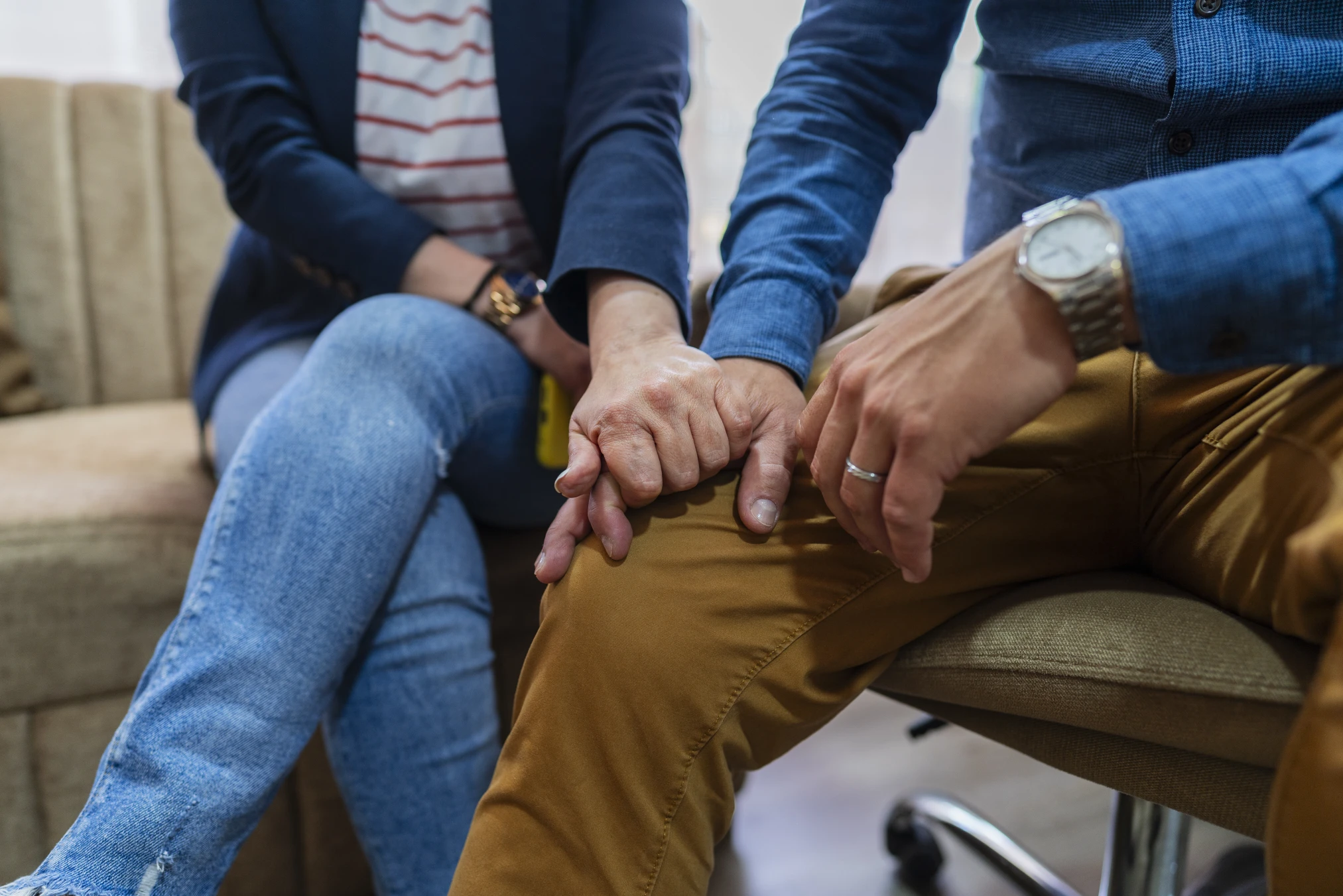 a couple holds hands while in counseling